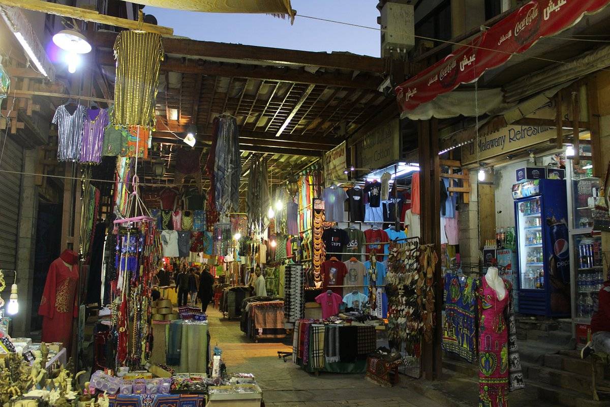 Un callejón estrecho iluminado con faroles en el zoco, lleno de telas y mercancías colgadas