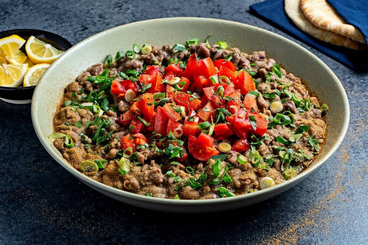 Ful Medames served in a bowl with olive oil and garnishes