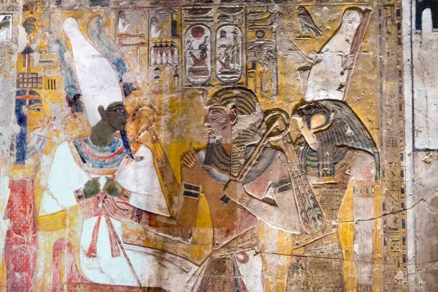 Vibrant wall paintings inside an ancient Egyptian tomb showing detailed figures and hieroglyphs